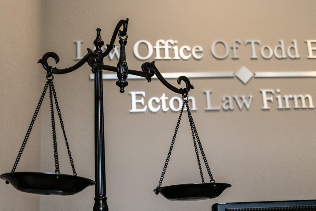 0O1A7673-1024x683 Scales of justice in front of Ecton Law Firm, P.A. office sign.